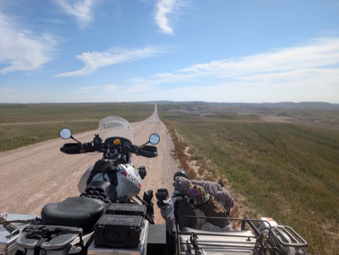 Badlands gravel, straight to the horizon. Tucked in with his blanket for the long haul.